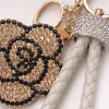 A golden diamond-encrusted flower-shaped keychain with a beige woven leather rope handle ring Application Scenario